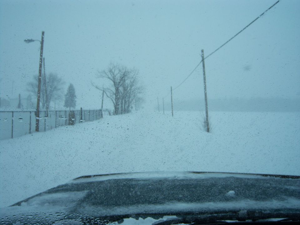Dark dashboard covered in snow, viewed from inside a vehicle during a snowstorm