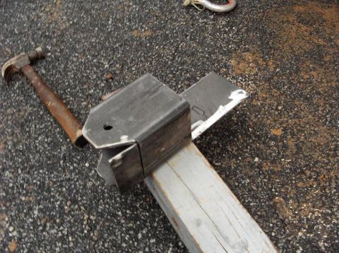 1990 Ford Bronco - A metal bracket and hammer are on the ground next to a piece of wood.
