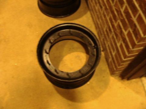 1990 Ford Bronco - A single black steel wheel rim is shown on a yellow surface, adjacent to a brick wall.