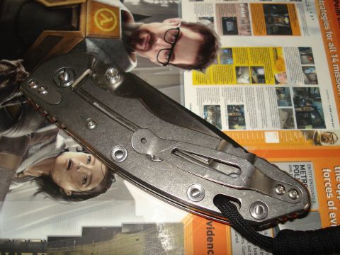 2000 Ford Crown Victoria - A folding knife is placed on top of several magazines with various images and text.