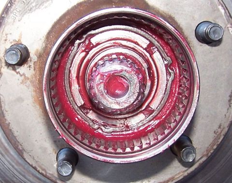 1990 Ford Bronco - This is a close-up view of a vehicle's wheel hub assembly, showing the internal components covered in red grease.
