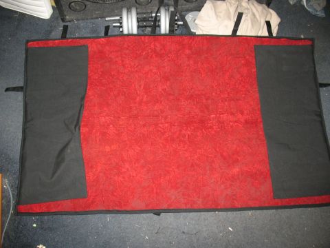 1997 Ford Crown Victoria - A red and black car cover is laid out on the floor, with weights and other items in the background.