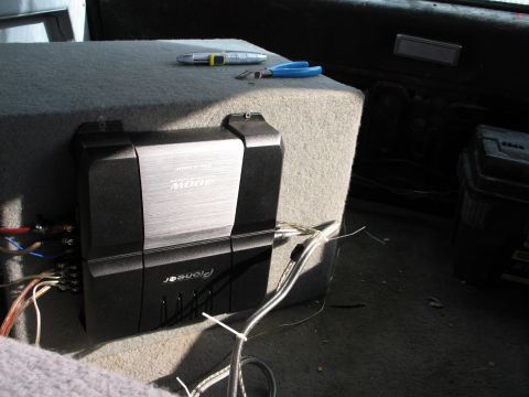 1995 Ford Bronco - A Pioneer amplifier is mounted on a subwoofer box inside a vehicle's interior.