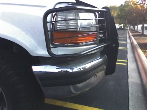 1996 Ford Bronco - Close-up of a white Ford truck's front corner, showing a black bull bar and chrome bumper.