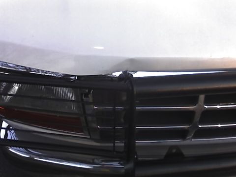 1996 Ford Bronco - Close-up of the front grille and headlight assembly on a white truck, showing damage to the hood.