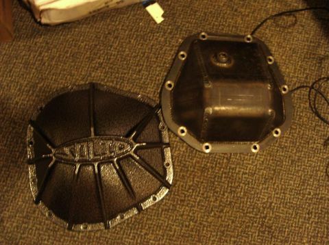 1990 Ford Bronco - Two differential covers are shown on a carpeted surface, one with a decorative pattern and brand name.
