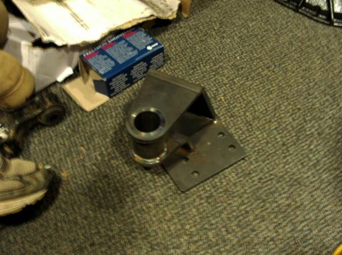1990 Ford Bronco - A metal bracket is shown on a carpeted floor, with a blue box and other objects in the background.