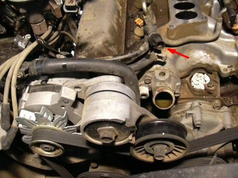 1991 Ford Bronco - Close-up view of engine parts, showing an alternator, drive belts, and part of the intake manifold.