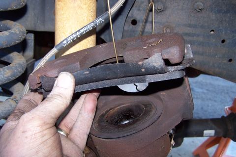 1990 Ford Bronco - Close-up of a brake caliper and rotor assembly, with text visible on the brake line.