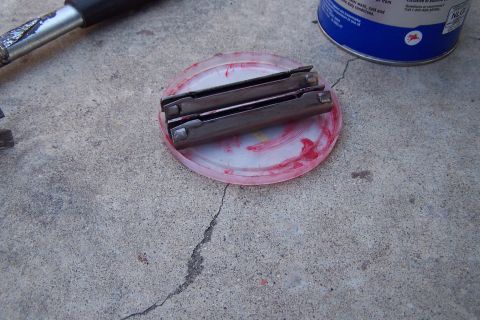 1990 Ford Bronco - Ball joint parts and grease on a concrete surface with a tool and can nearby.