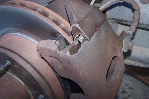 1990 Ford Bronco - A close-up view of a vehicle's brake caliper and rotor, showing signs of wear and rust.