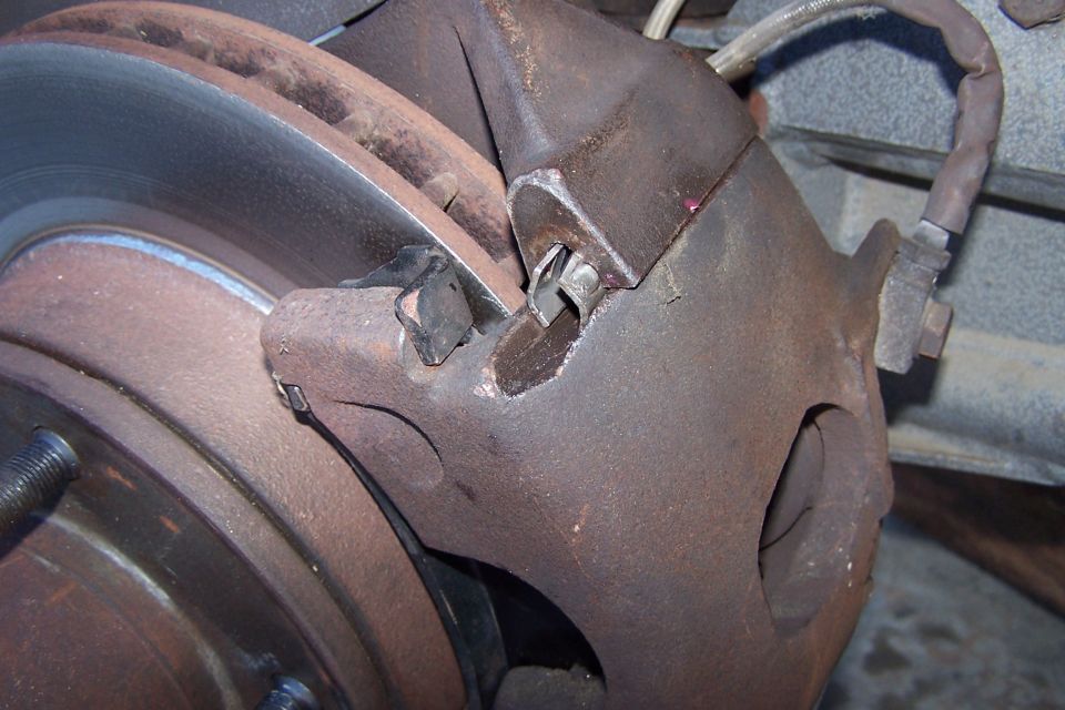 Close-up of a rusty brake caliper and rotor assembly