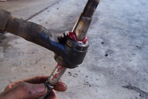 1990 Ford Bronco - Ball joint assembly being greased, likely for a vehicle's suspension system.