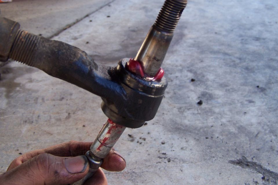 Close-up of a greased ball joint assembly with a threaded stud and a socket