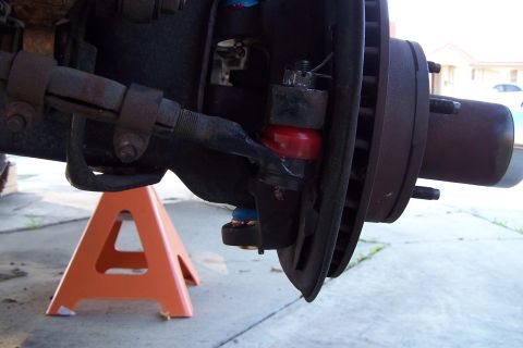 1990 Ford Bronco - Close-up view of a vehicle's ball joint assembly, supported by an orange jack stand.