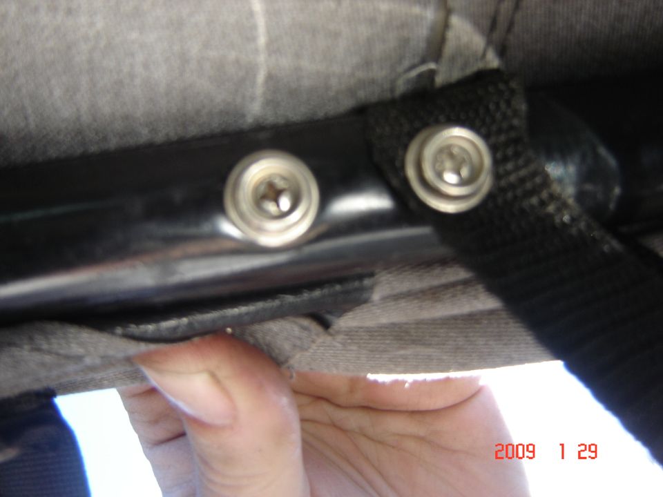 Close-up of two metal snap fasteners on a black tube frame with cloth fabric and a hand