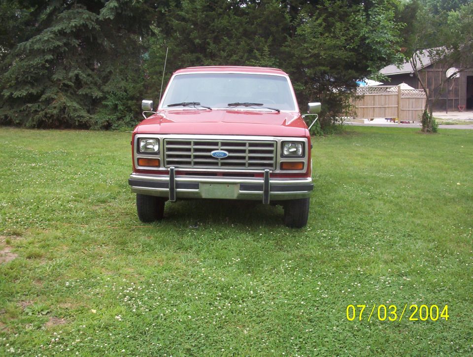 Red Ford Bronco parked on grass, front view. Chrome grille and bumper. Date stamp 07/03/2004