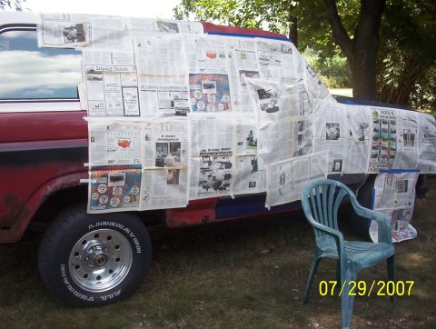 1985 Ford Bronco - Truck body covered in newspaper, ready for paint. A green chair sits nearby.