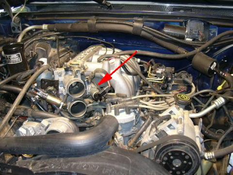 1991 Ford Bronco - Close-up view of an engine bay, with a red arrow highlighting the throttle body assembly.