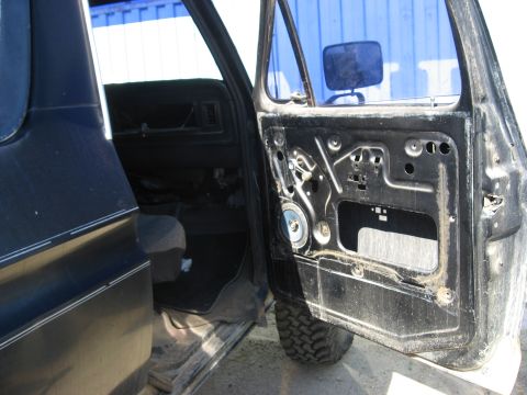 1979 Ford Bronco - The interior of a 1979 Ford Bronco is visible, with the driver's side door removed to expose the inner workings.