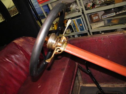 1913 Ford Model T - The interior of a 1913 Ford Model T shows its steering wheel, brass controls, and red leather upholstery.