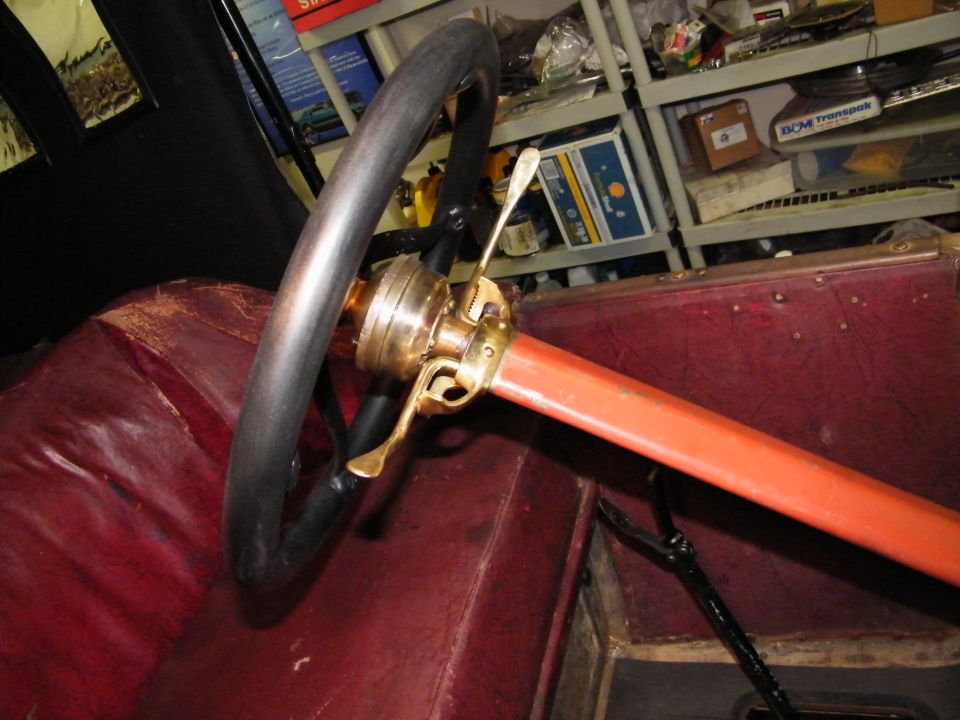 Steering wheel, brass controls, and red leather interior of a 1913 Ford Model T