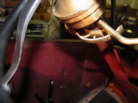 1913 Ford Model T - A close-up view of the steering wheel and a brass component within the interior of a vintage automobile.