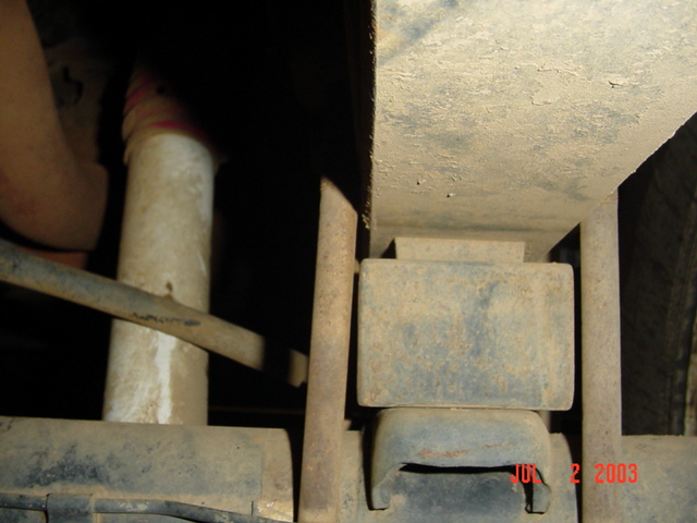 Underbody view of a rusty leaf spring, shackle and frame rail dated July 2003