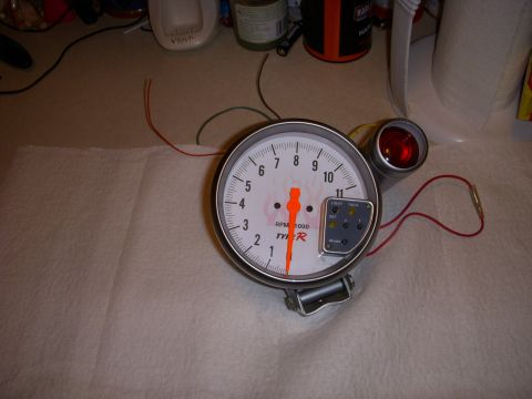 1995 Ford Bronco - A tachometer gauge with a red indicator light and visible wiring is shown on a surface.