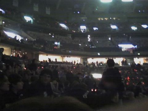 2004 Land Rover Land Rover - A large crowd is gathered inside a stadium, with many lights illuminating the space.