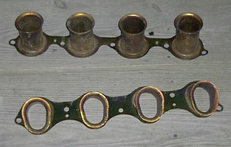 Two automotive intake manifold gaskets on a wooden surface.