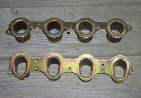 1997 Ford Taurus - Two intake manifold gaskets are shown laid out on a wooden surface. The top gasket has four circular openings, while the bottom gasket has…