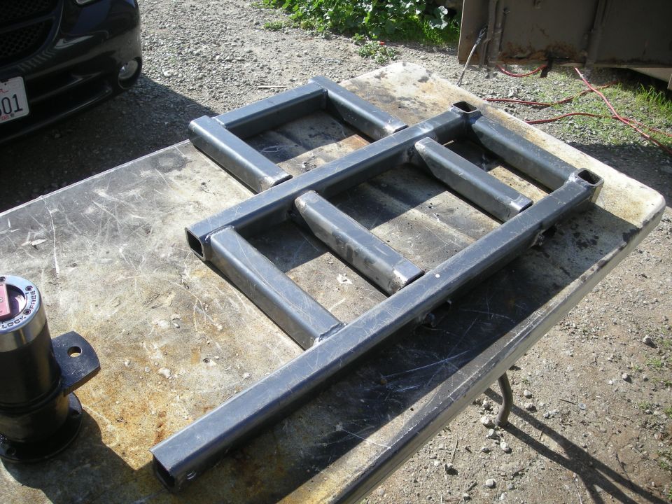 Custom metal rack on workbench, black vehicle in background.