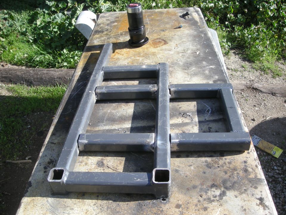 Metal frame made of square tubing on a workbench outdoors.