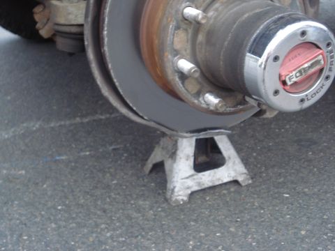 1994 Ford E350 - Close-up view of a vehicle's wheel hub assembly being supported by a jack stand.