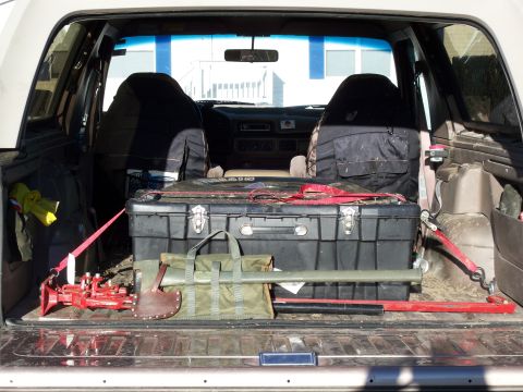 1996 Ford Bronco - The open rear cargo area of a Ford Bronco is filled with various tools and equipment, including a large black toolbox, a green canvas bag,…