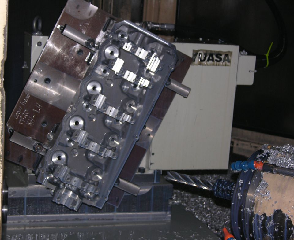 Aluminum cylinder head being machined in a CNC mill with metal chips
