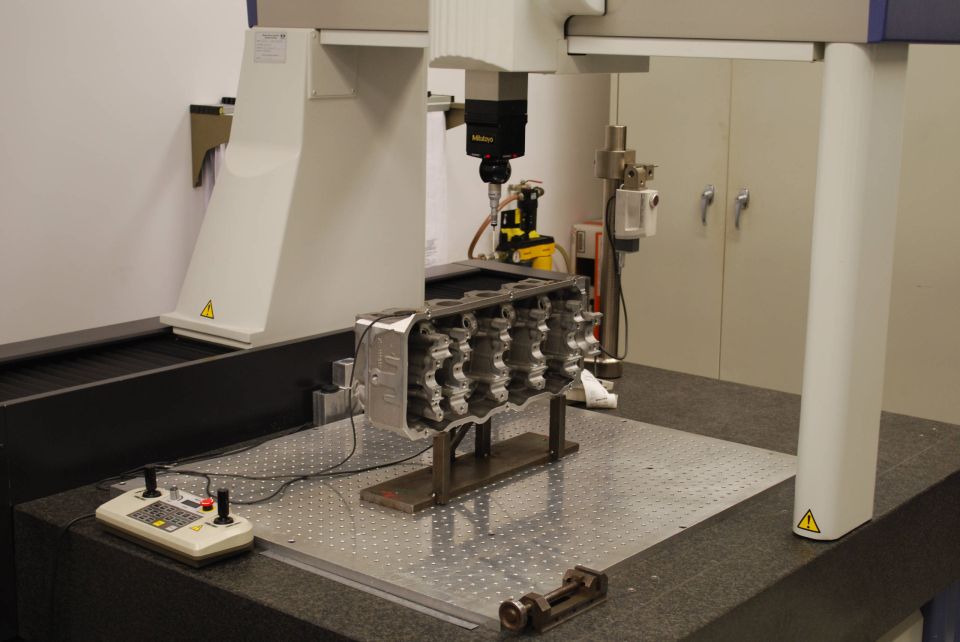Aluminum cylinder head being measured on a Mitutoyo CMM in a metrology lab