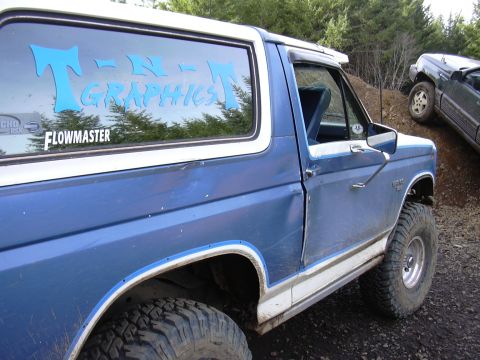 1991 Ford Bronco - The side view of a blue Ford Bronco with a white roof and trim is shown, featuring blue "T-N-GRAPHICS" text and a "FLOWMASTER" sticker on t…