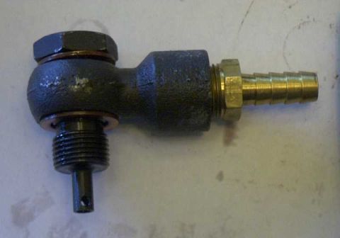 1997 Ford Taurus - A close-up view of a brass hose barb fitting attached to a dark-colored valve body, likely a fuel or vacuum component.