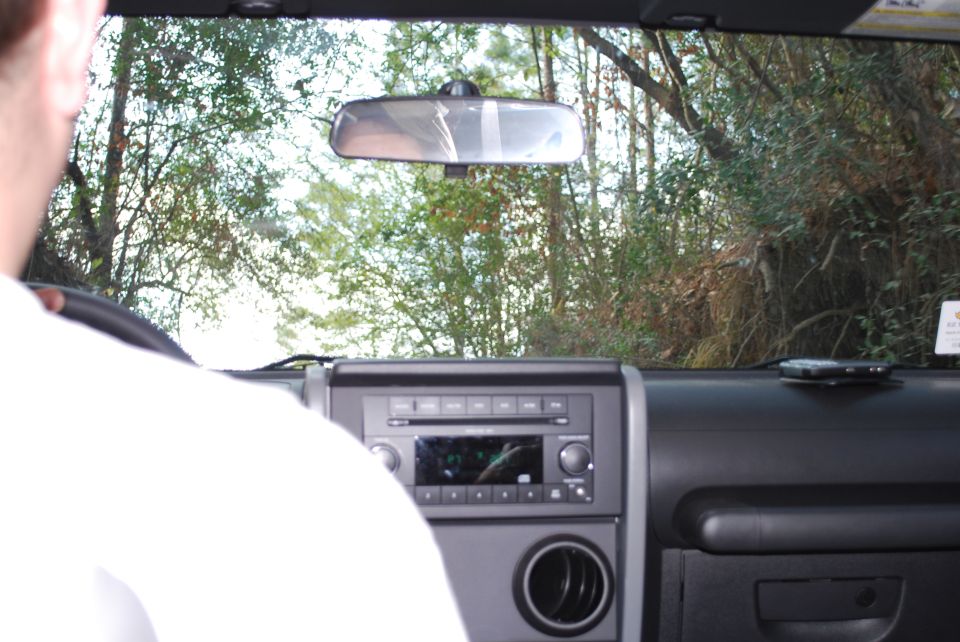 Interior view of a Jeep Wrangler, looking forward through the windshield at trees.