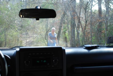2008 Jeep Wrangler - View from inside a Jeep Wrangler looking through the windshield at a woman walking towards the vehicle in a wooded area. The dashboard and…