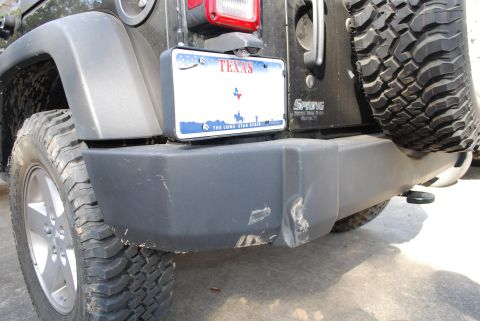 2008 Jeep Wrangler - The rear bumper of a black Jeep Wrangler is shown with a Texas license plate mounted. The bumper has visible scuffs and a dent on the passe…