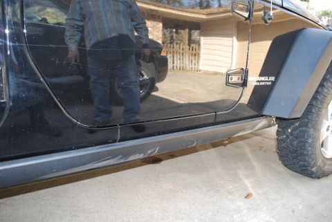 2008 Jeep Wrangler - The side of a black Jeep Wrangler Unlimited is shown, focusing on the driver's side door and fender. Scratches are visible on the door and…