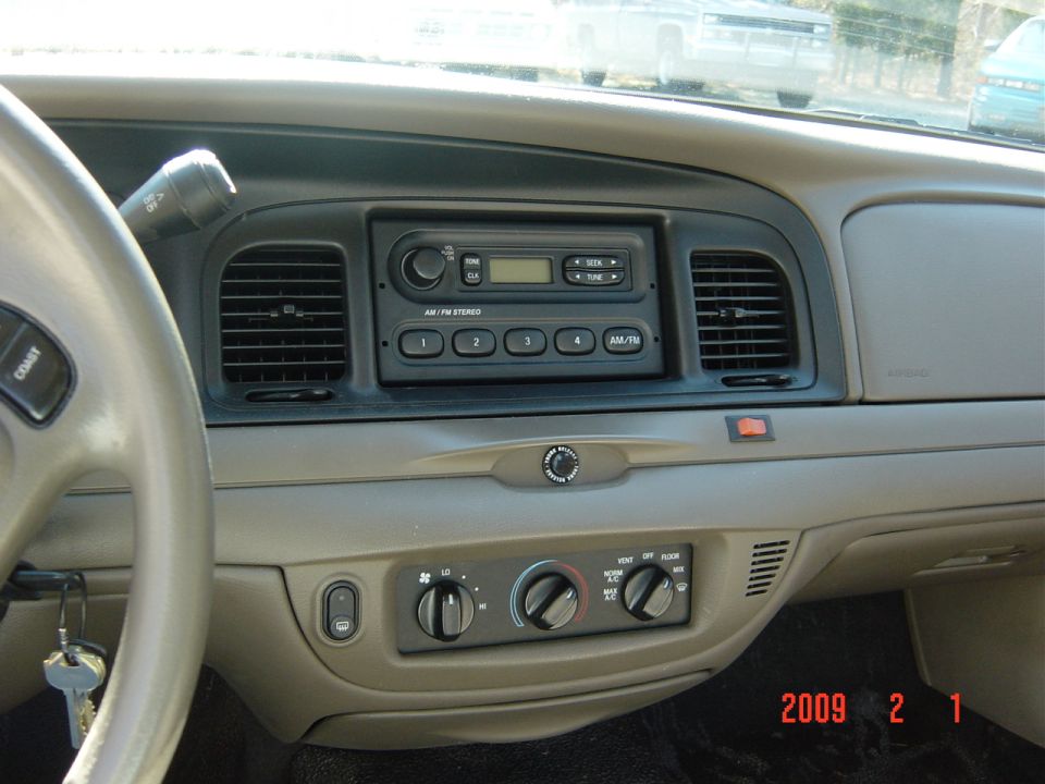 Interior dashboard of a Ford Crown Victoria, showing steering wheel, radio, and climate controls.