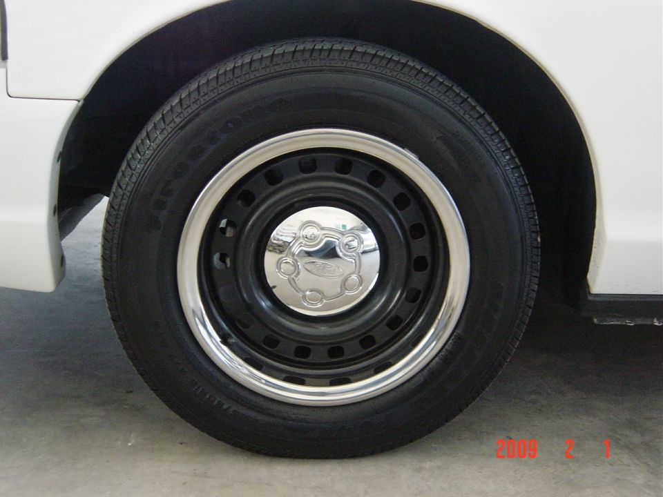 White 2002 Ford Crown Victoria wheel with chrome hubcap and black rim