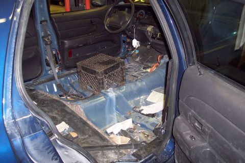 2001 Ford Crown Victoria - The interior of a blue sedan shows a stripped-down cabin with exposed wiring and debris on the floor.
