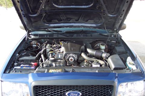 2001 Ford Crown Victoria - The engine bay of a blue Ford Crown Victoria, showing the engine and surrounding components with the hood raised.