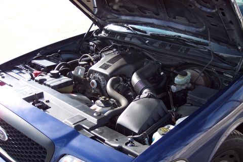 2001 Ford Crown Victoria - The engine bay of a blue 2001 Ford Crown Victoria is visible with the hood raised.