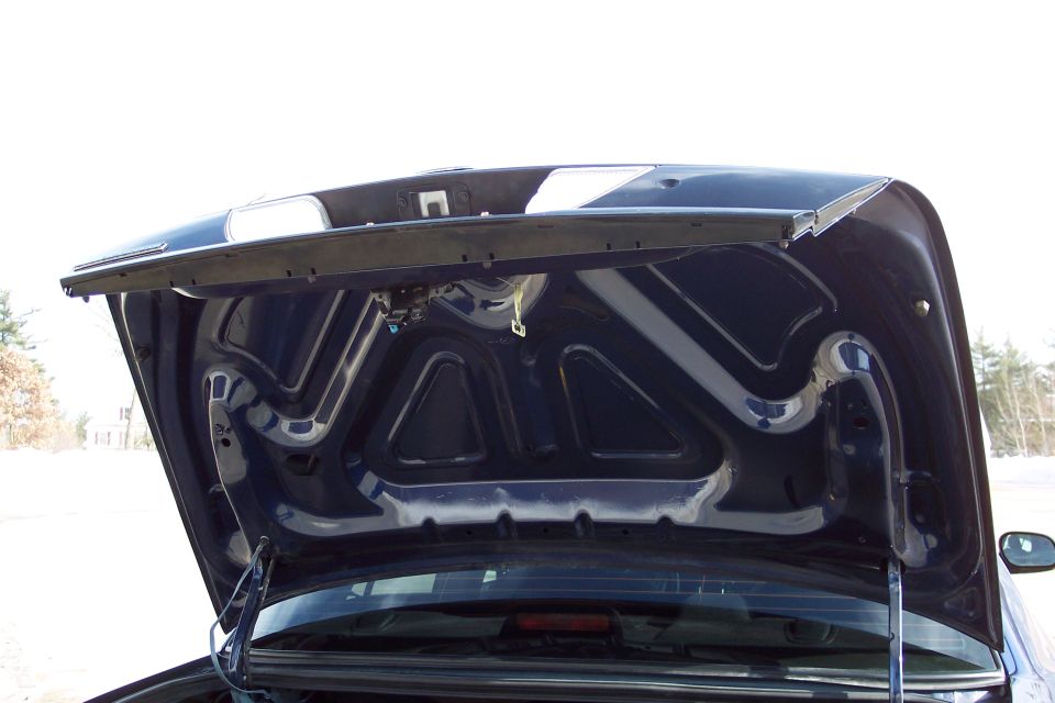 Dark blue car hood interior, open, showing latch mechanism and underside bracing